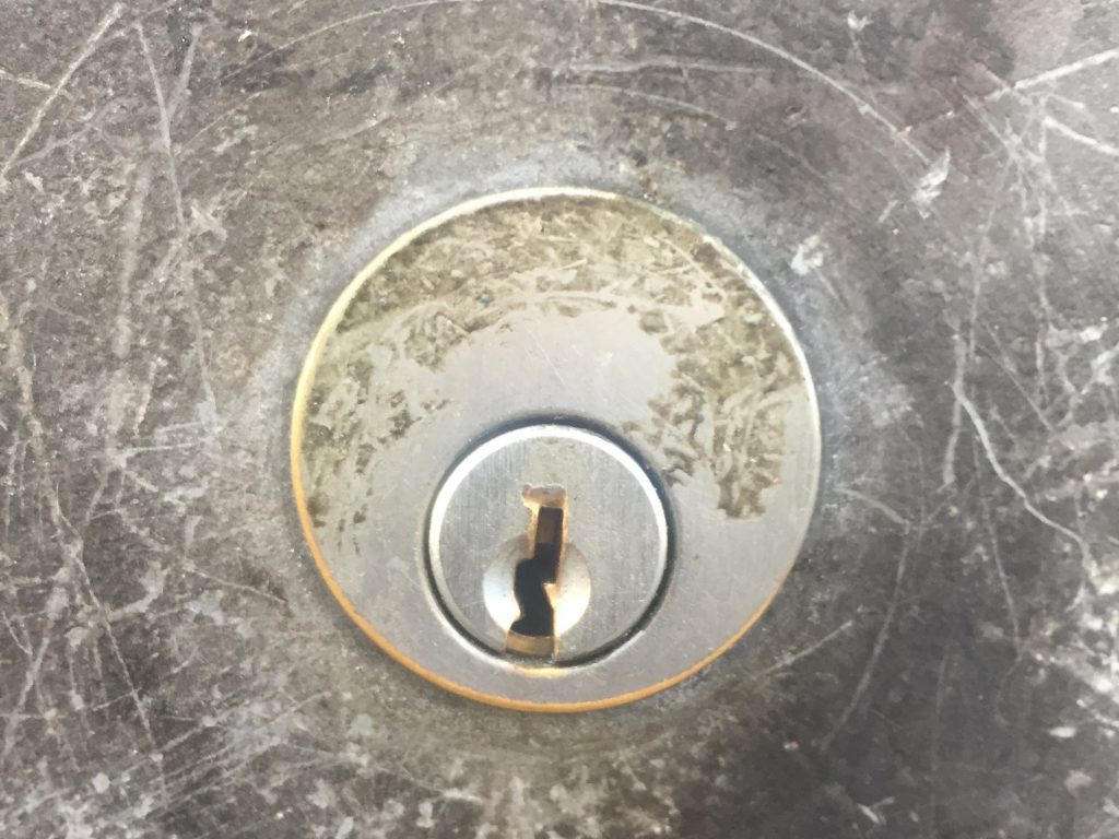 Scratched up metal surface with lock in center