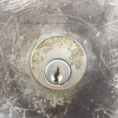 Scratched up metal surface with lock in center