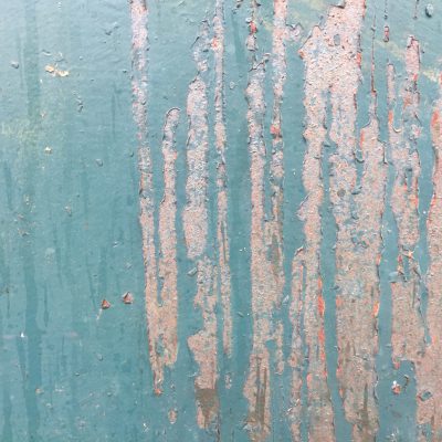 Rust metal with chipped teal paint creating grungy surface