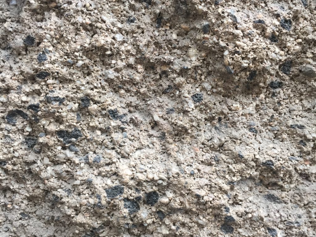 Grey cement texture with composite rocks and black spots