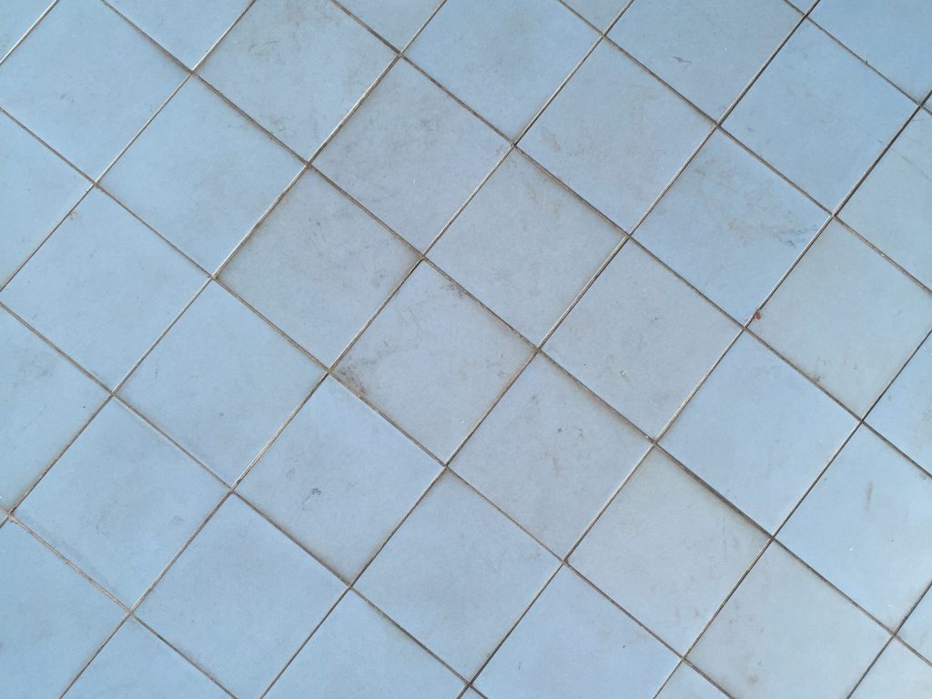 Light blue tiles that are dirty and have some scuffs