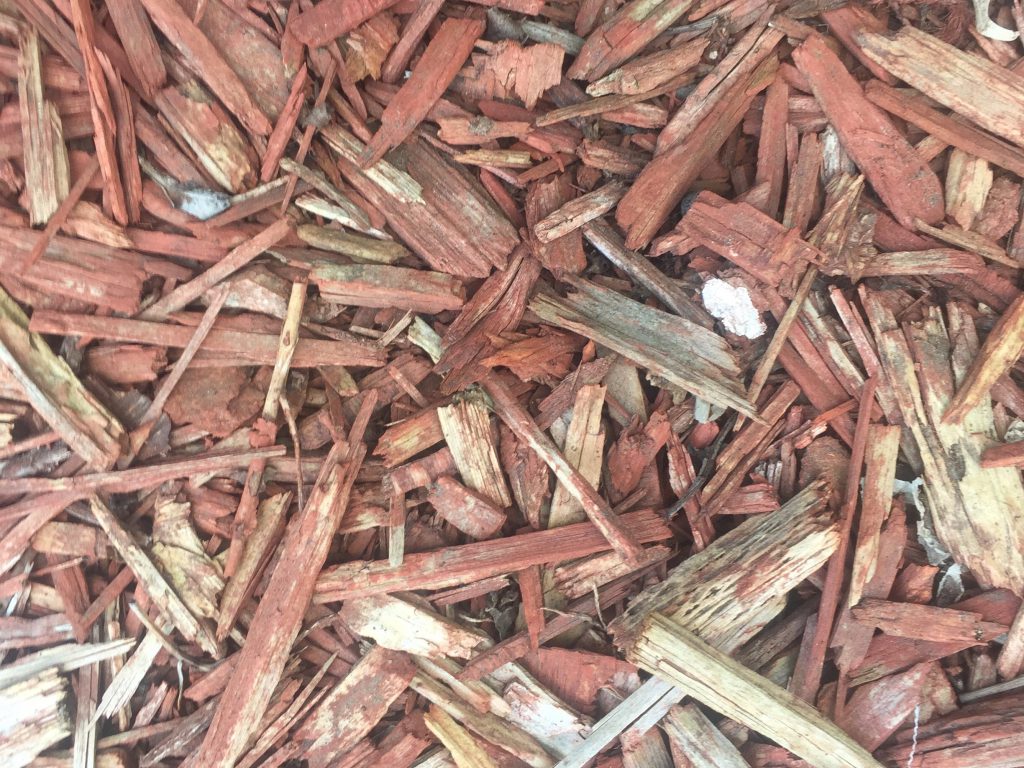 Red and white chunks of wood in mulch bed