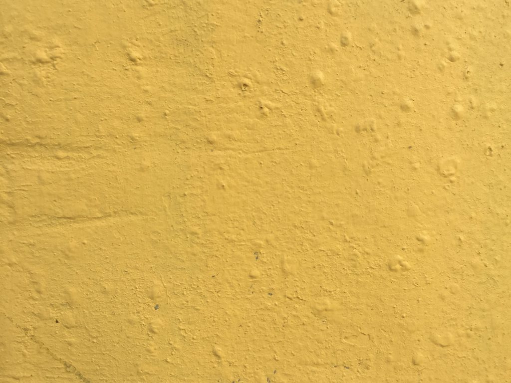 Concrete wall with lots of texture and yellow paint