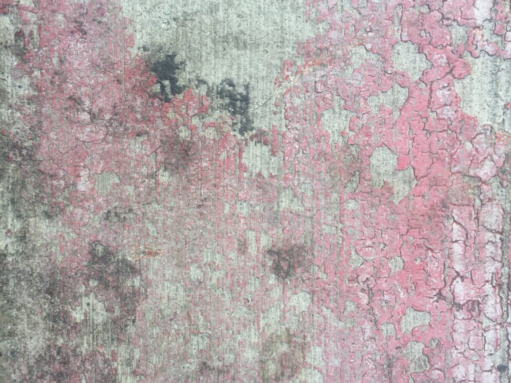 Cracked red paint on dirty concrete street