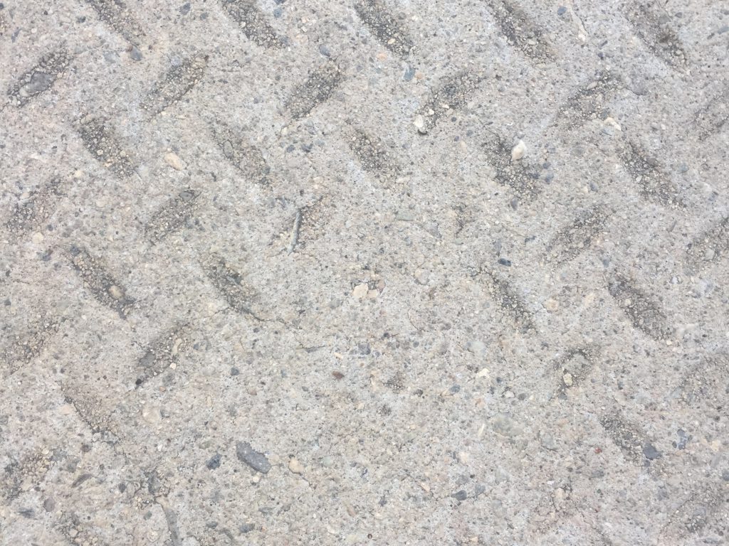 Light grey concrete over metal manhole cover