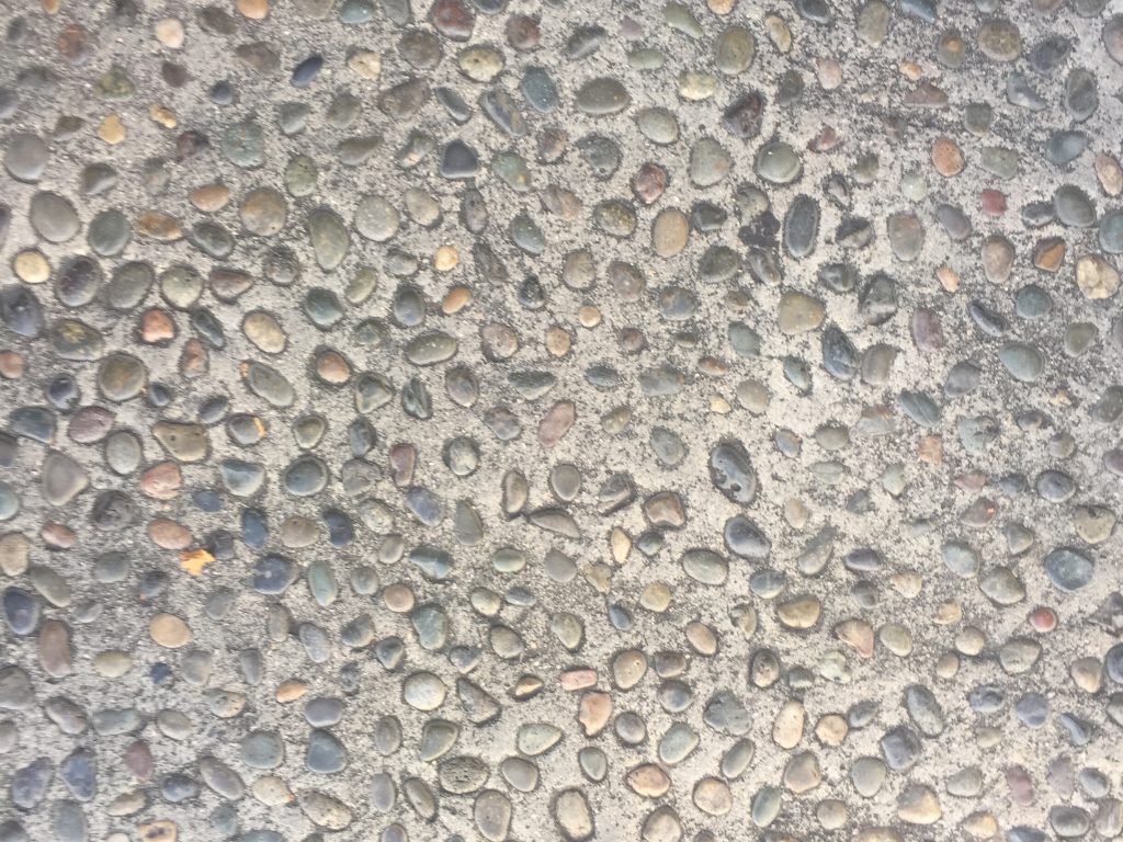 Concrete with embedded colorful pebbles on sidewalk slab