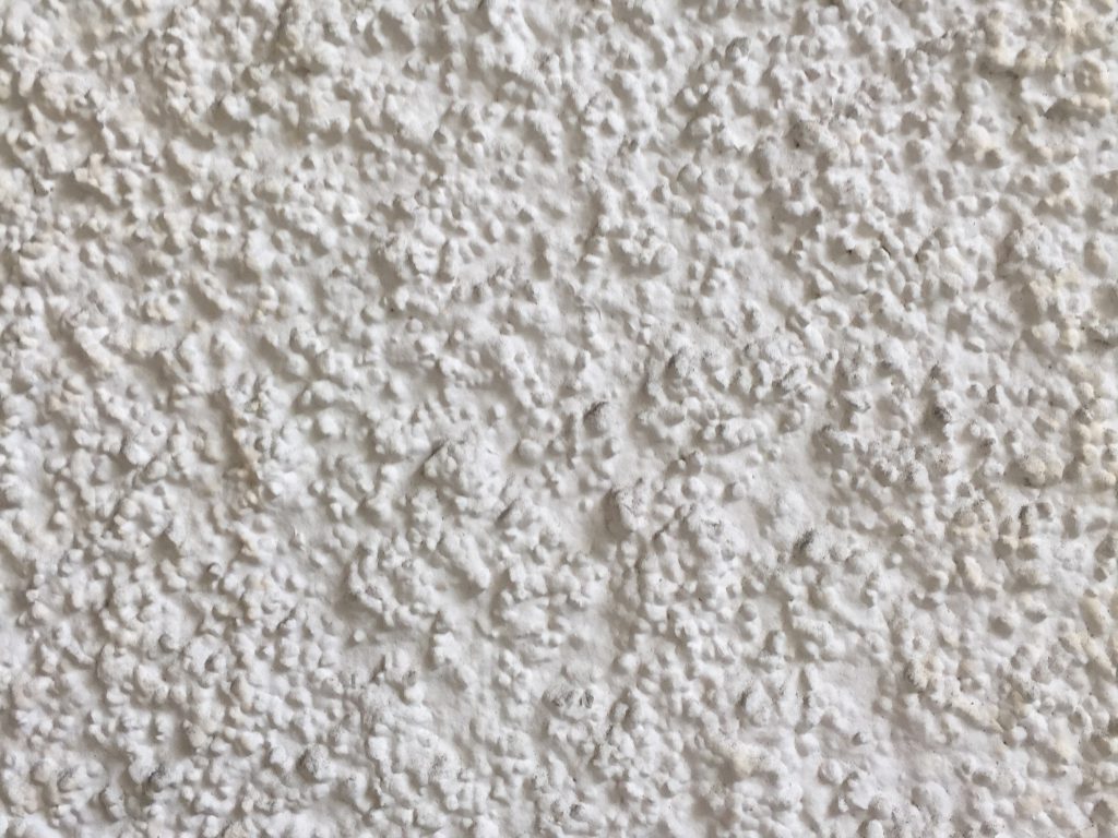 xtreme close up of off white stucco pattern revealing layers of bumps creating various shapes and shadows.