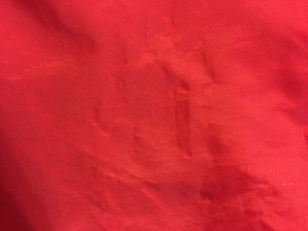 Bold red plastic fabric bag with wrinkles stock texture