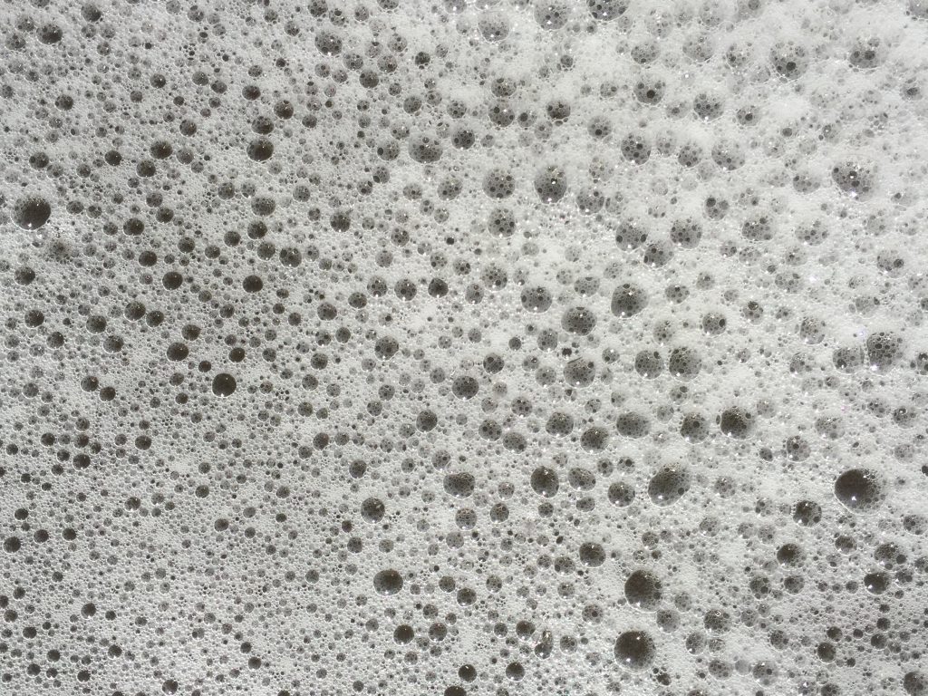 Layer of thin white sea foam with patterns of bubbles