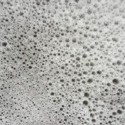 Layer of thin white sea foam with patterns of bubbles