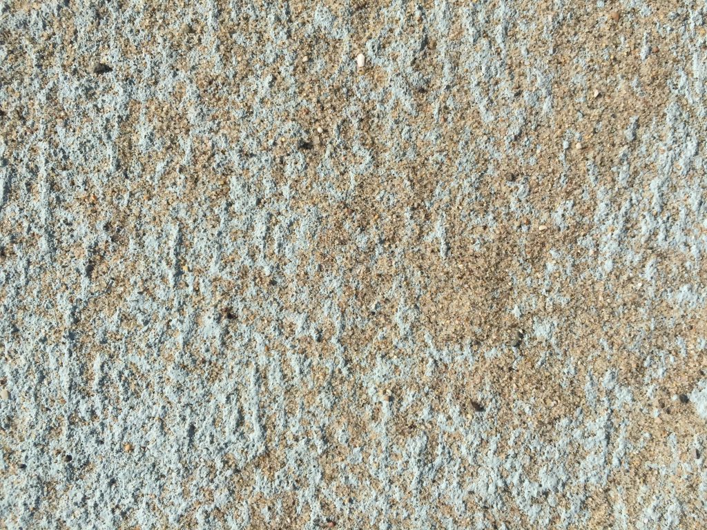Teal textured surface covered with sand