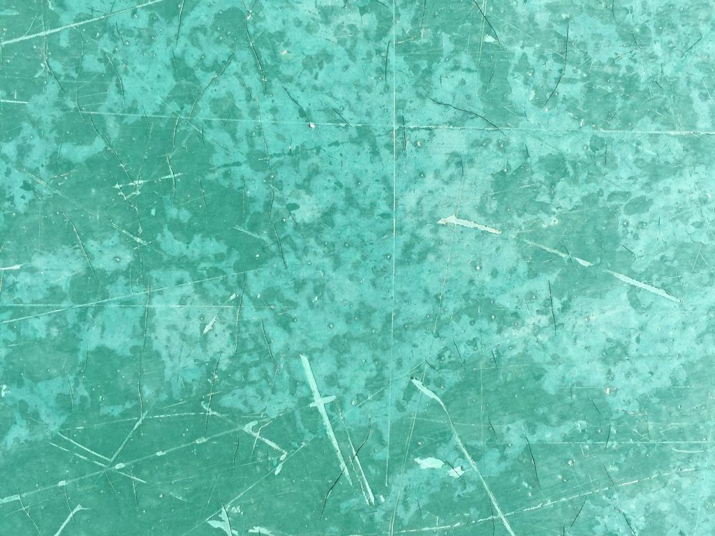 Intensely cracked and discolored green paint