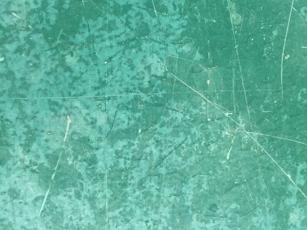 Close up of beat up green surface with lots of scratches