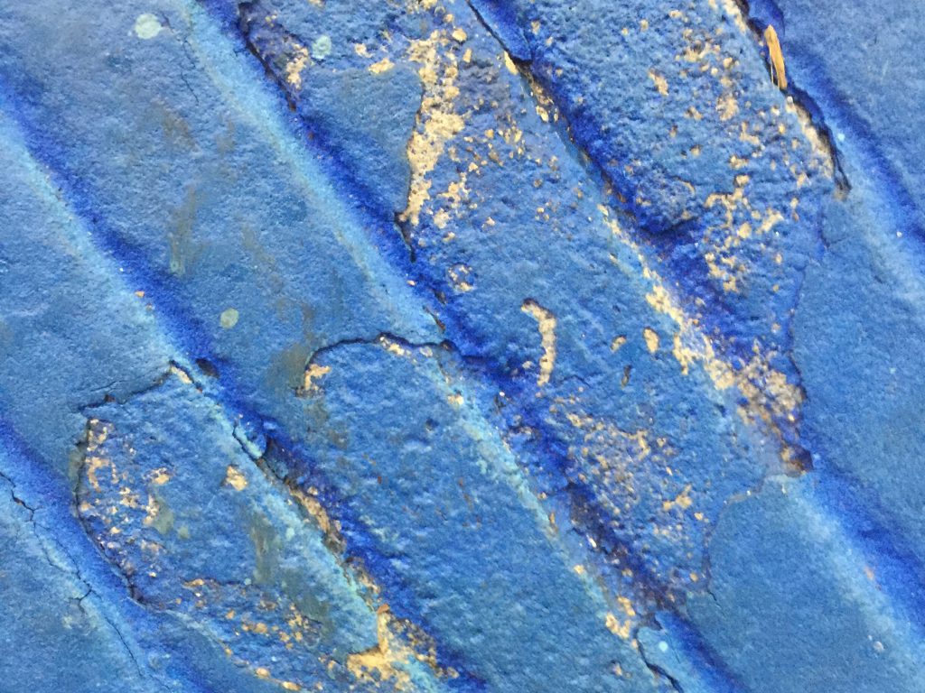 Diagonal grooved dirty blue paint on concrete