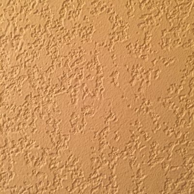 Yellow paint on textured stucco wall