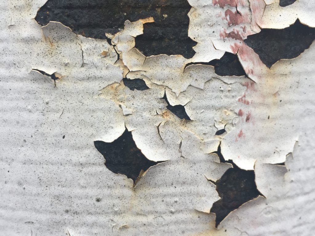 Cracked and peeling white paint on dark surface