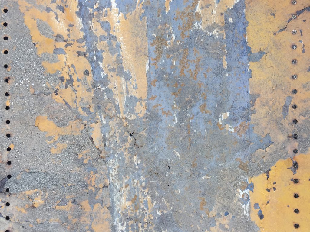 Flaking yellow paint on hard metal