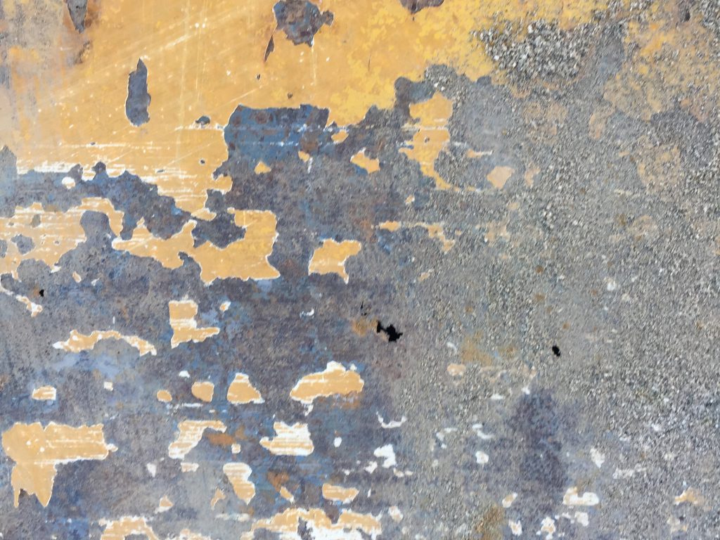 Chipping yellow paint on dark metal