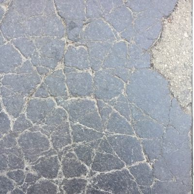 Cracked asphalt with chunk of concrete