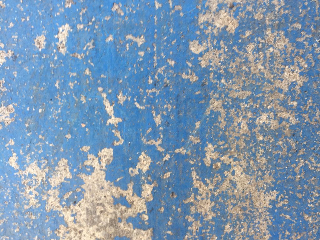 Light colored concrete with chipping blue paint