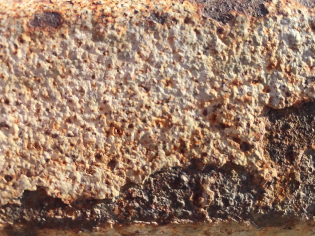 Layers of metal corrosion featuring white and dark brown