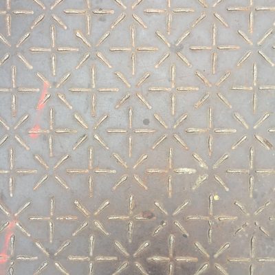 Steel utility cover with pattern of stars and plus symbols welded to top