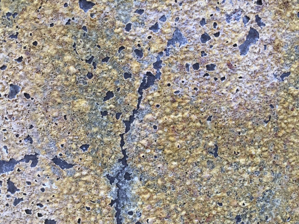 Detailed shot of pottery with thin crumbling pale yellow layer over dark surface