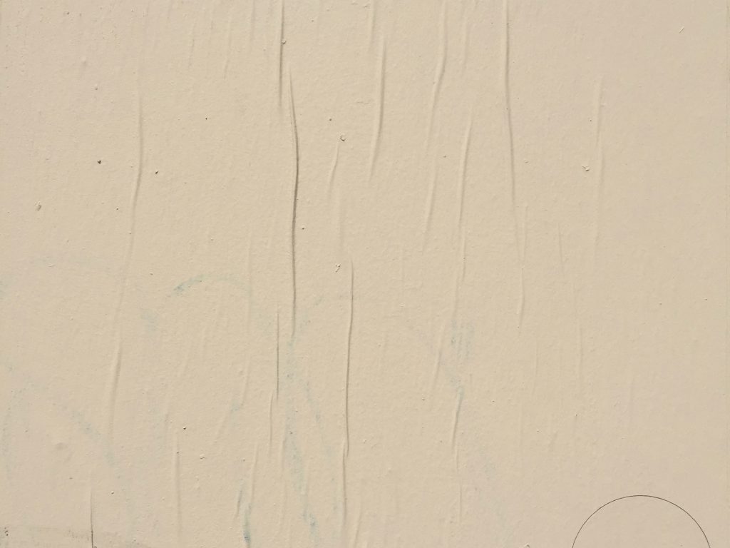 Coat of off white paint on wall with wrinkled paper