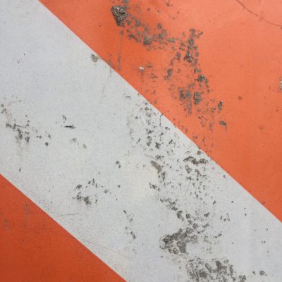 Deep orange and off white street sign with dirty texture clumps