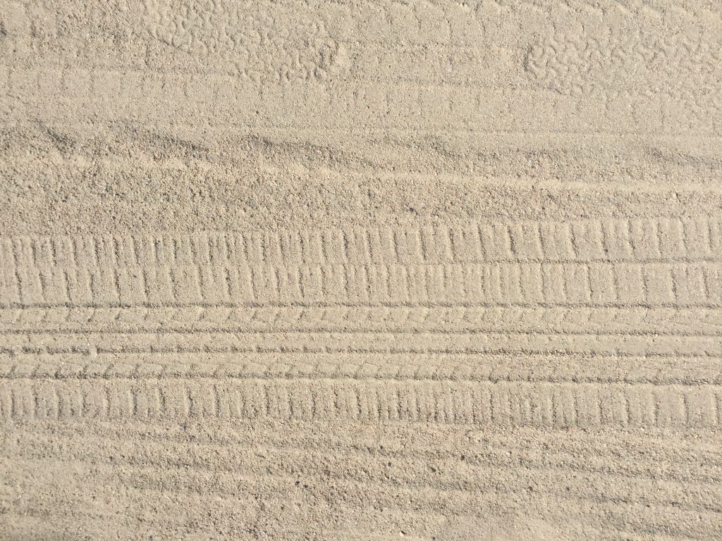 Light brown sand beach with tire marks