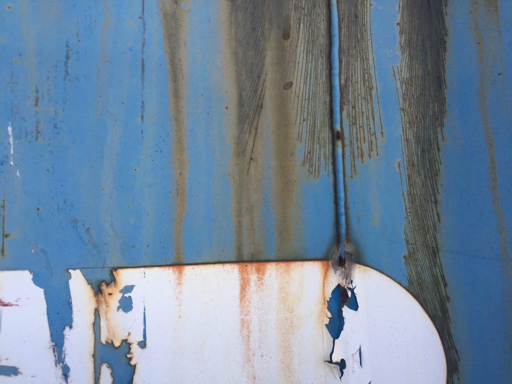 Dull blue paint with rust seeping through cracked paint