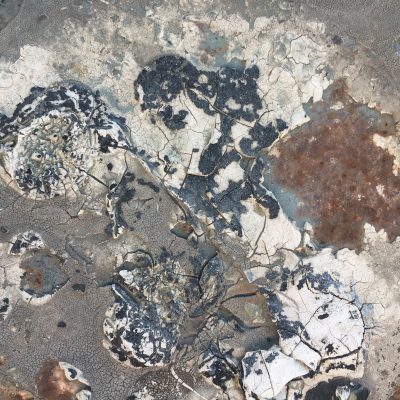 Tar and white paint covering rusted metal