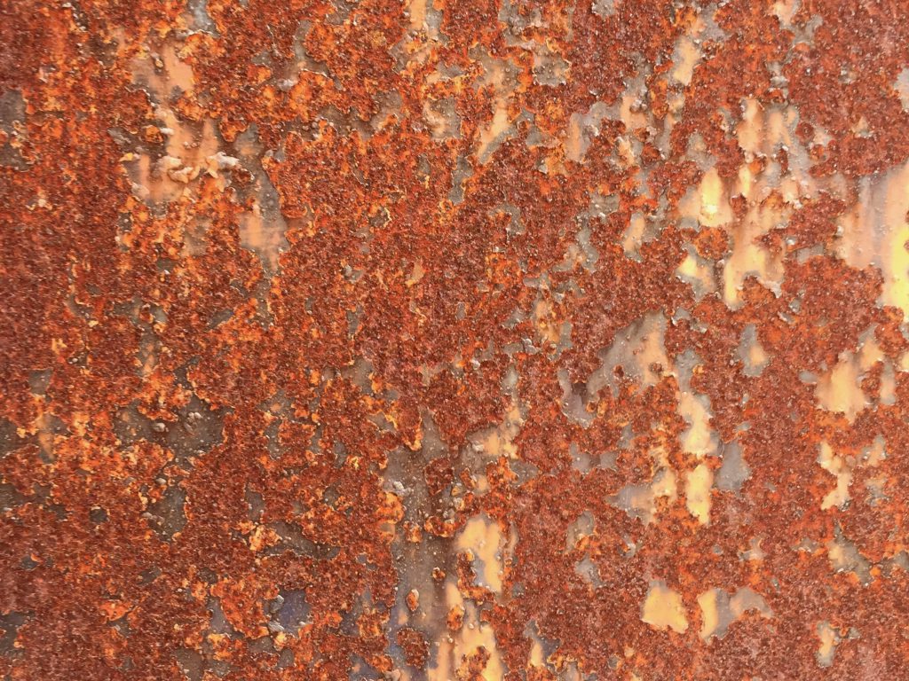 Flaking red rust on a wall with discolored surface