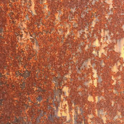 Flaking red rust on a wall with discolored surface