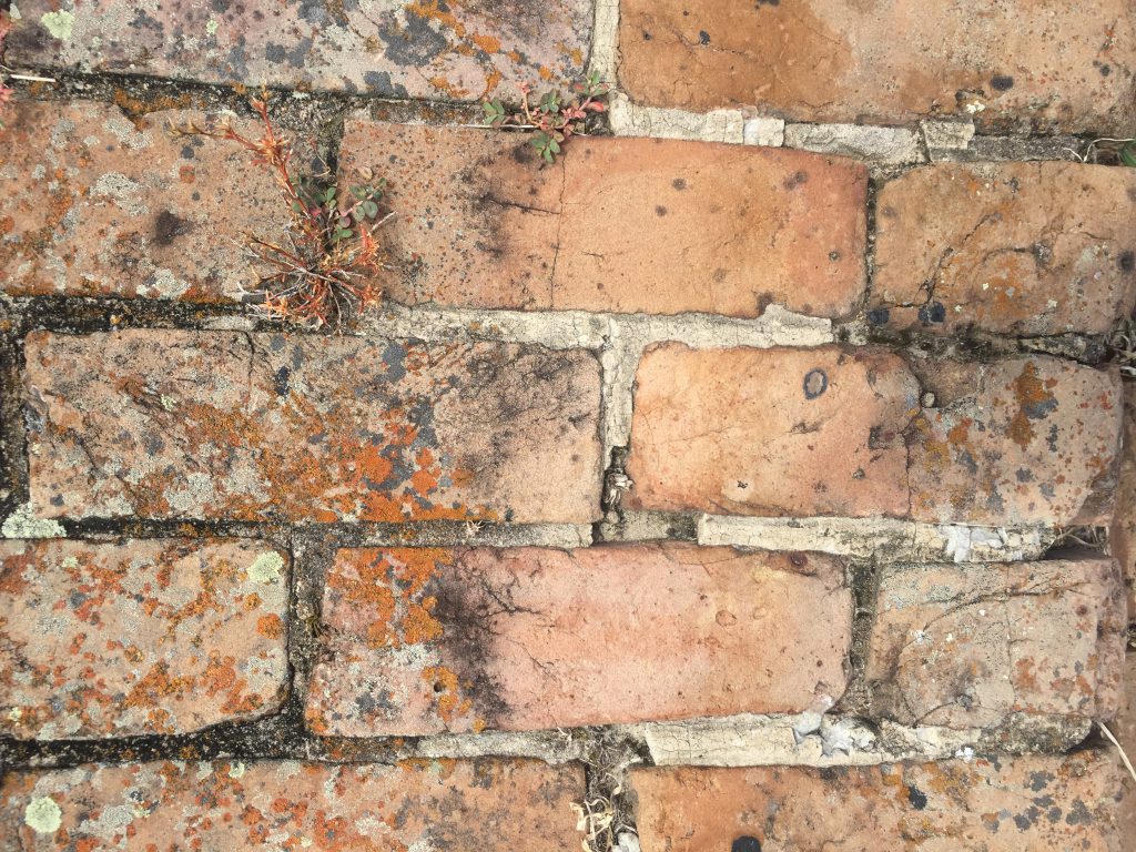 Faded and spotty cracked brick wall