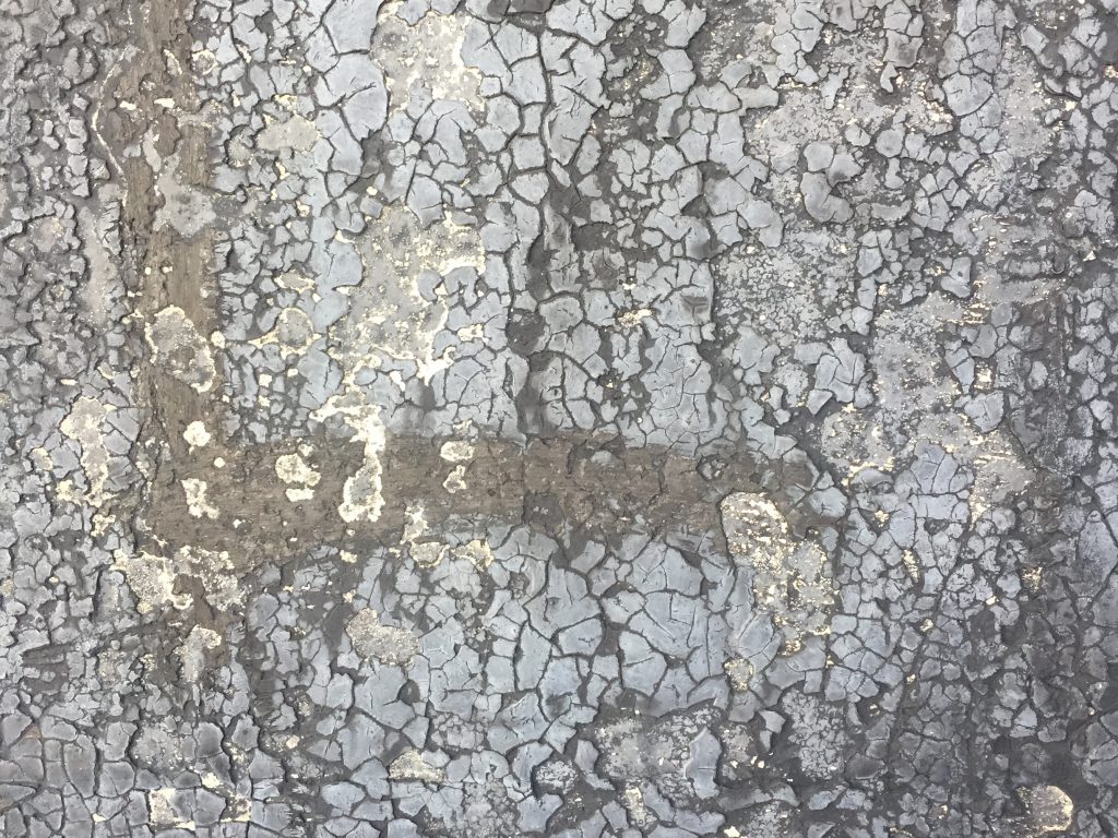 Dried out and cracking tar on concrete