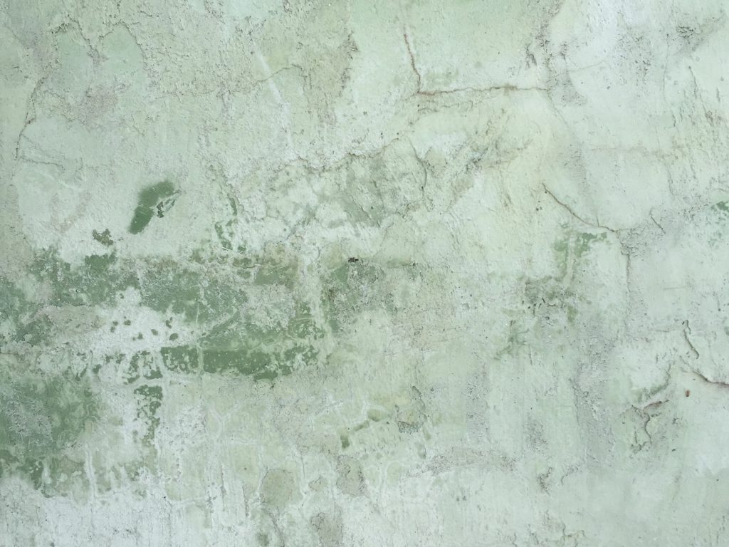 Green tinted layers of plaster cracking
