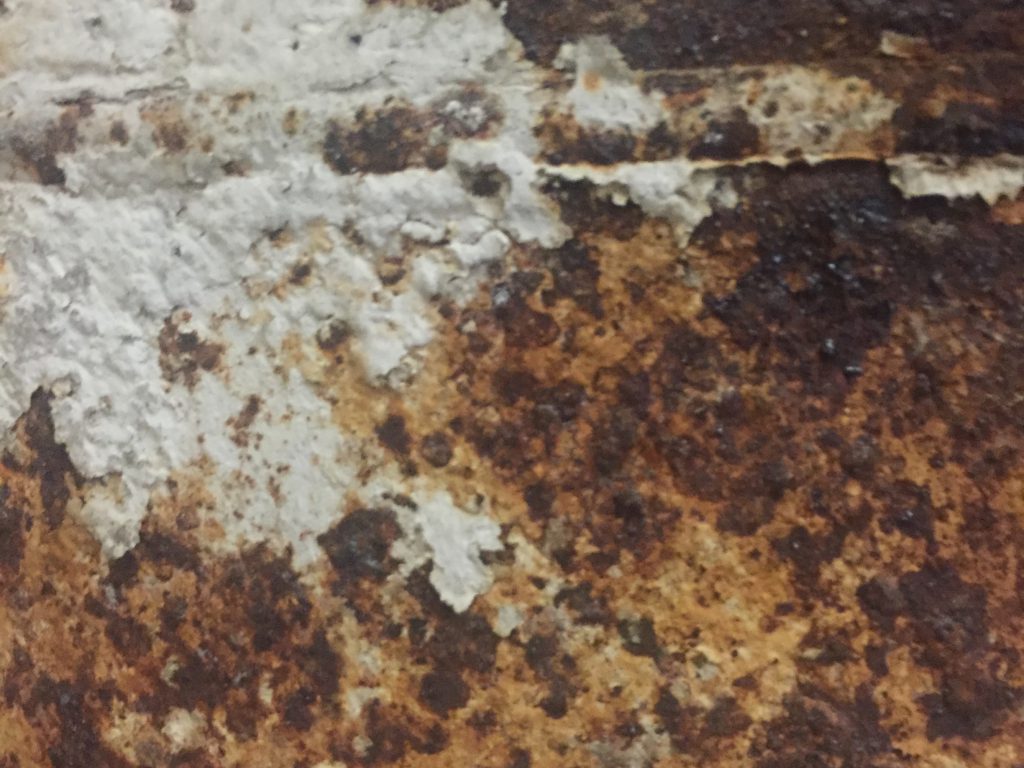 Grungy brown corrosion and rust with white paint