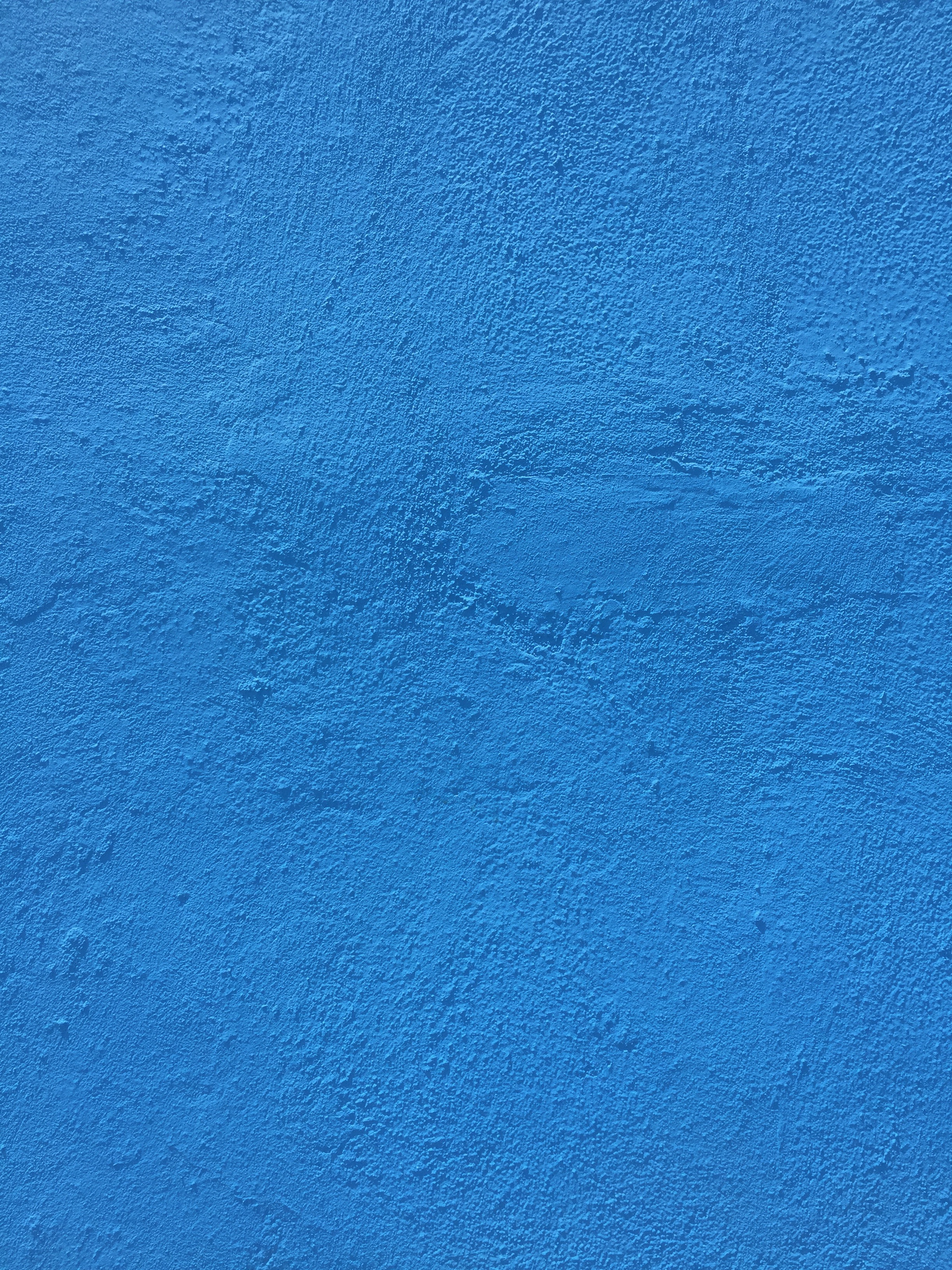 Bright blue paint over concrete wall