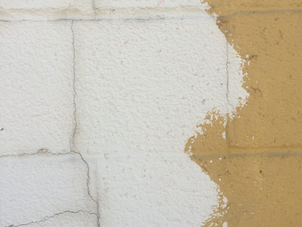 White and yellow paint over cracking cinderblocks