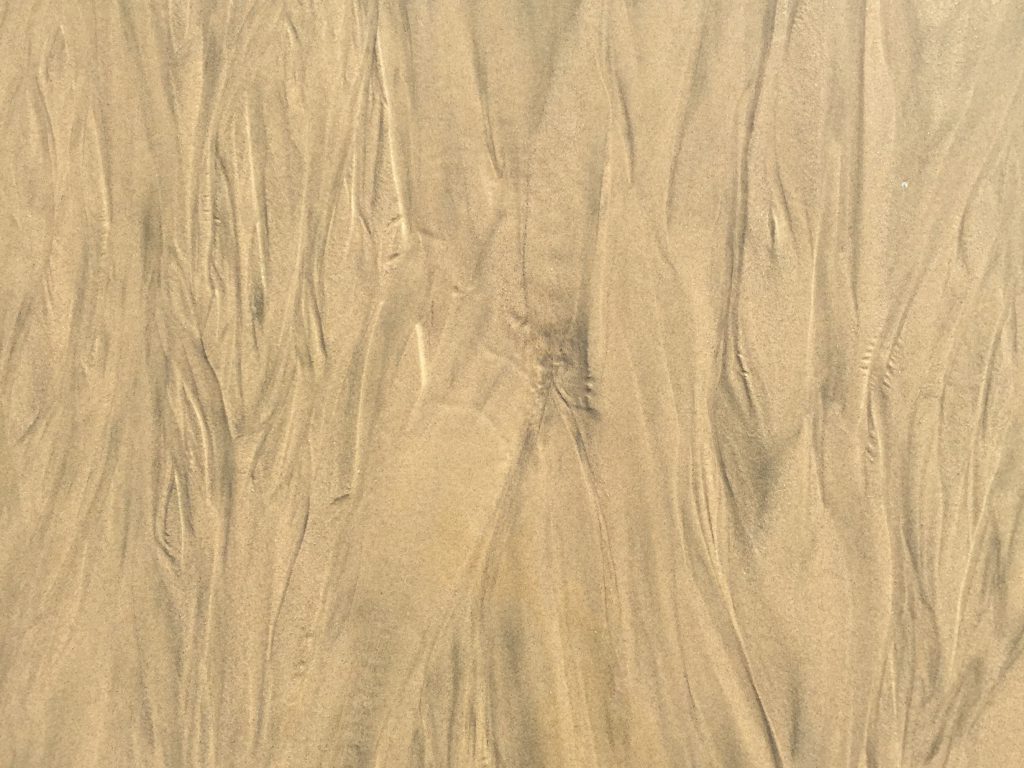 Wet sand with streaks running vertically and slight dark areas