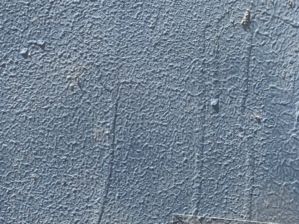 Coarse stucco wall covered in light blue paint