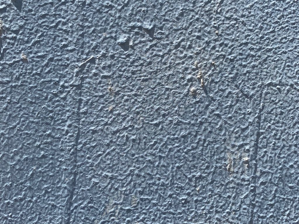 Baby blue paint over highly textured stucco wall