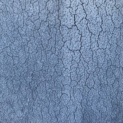 Splintering cracks on bumpy off white blue surface