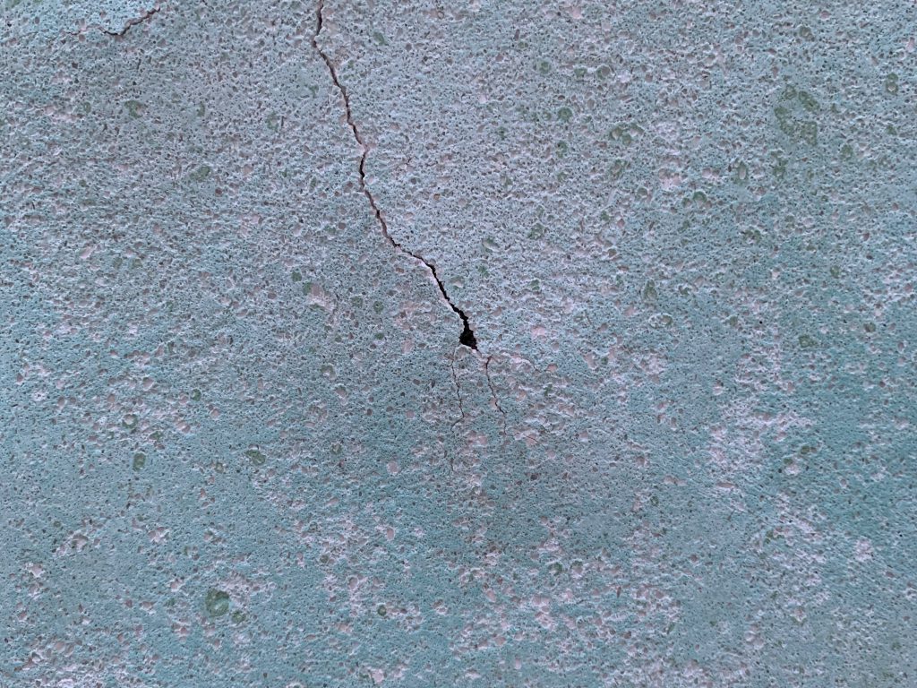 Turquoise color over corroded and cracked wall