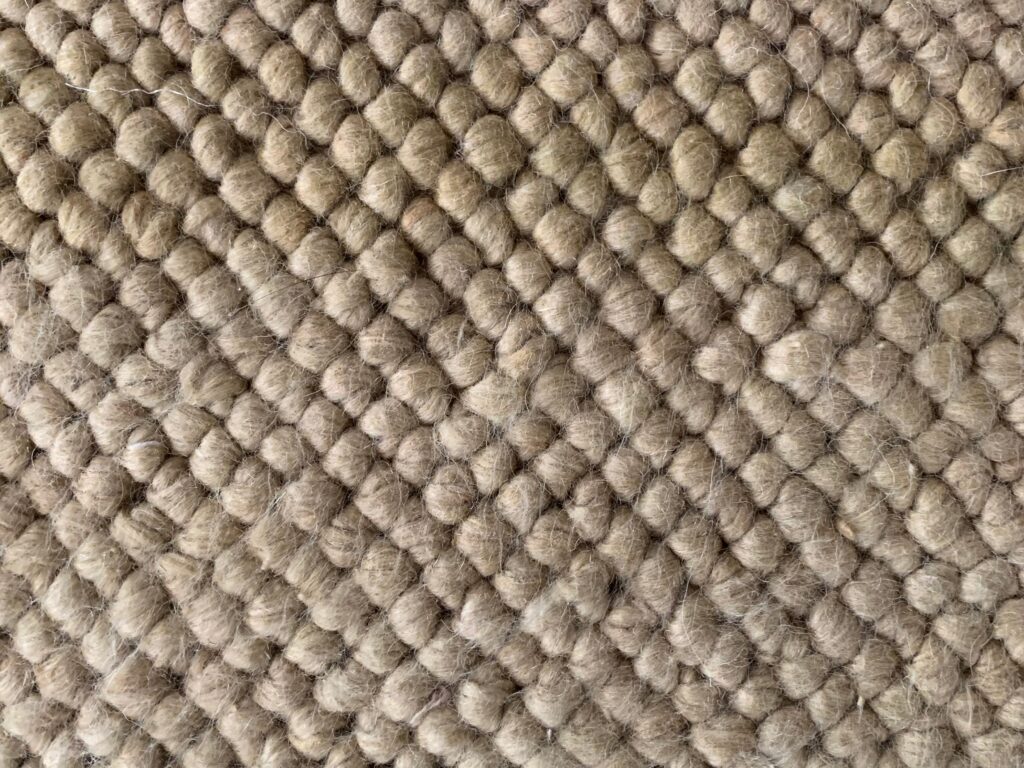 Close up off white worn down closed loop carpet