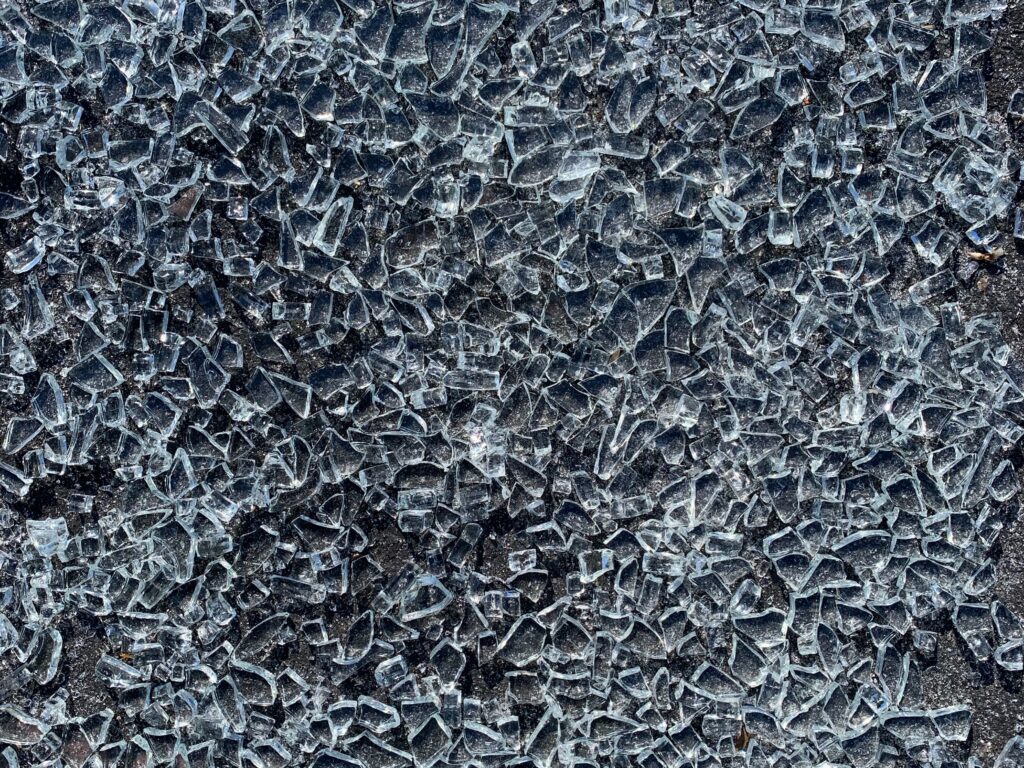 Blue and white shards of glass over black asphalt