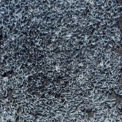 Blue and white shards of glass over black asphalt