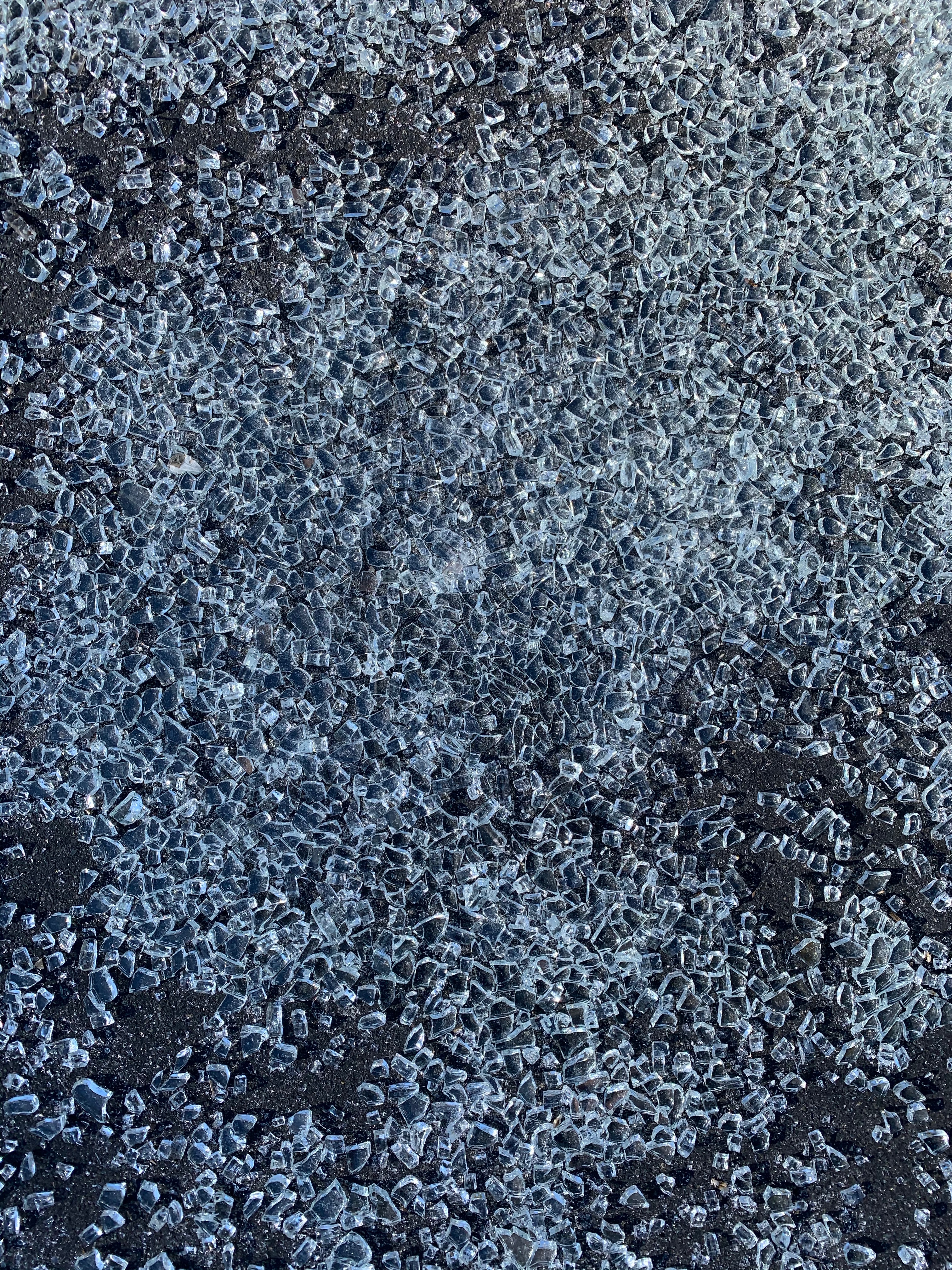 Chunks of broken glass scattered over black asphalt