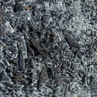 Close up of shards of glass on black asphalt